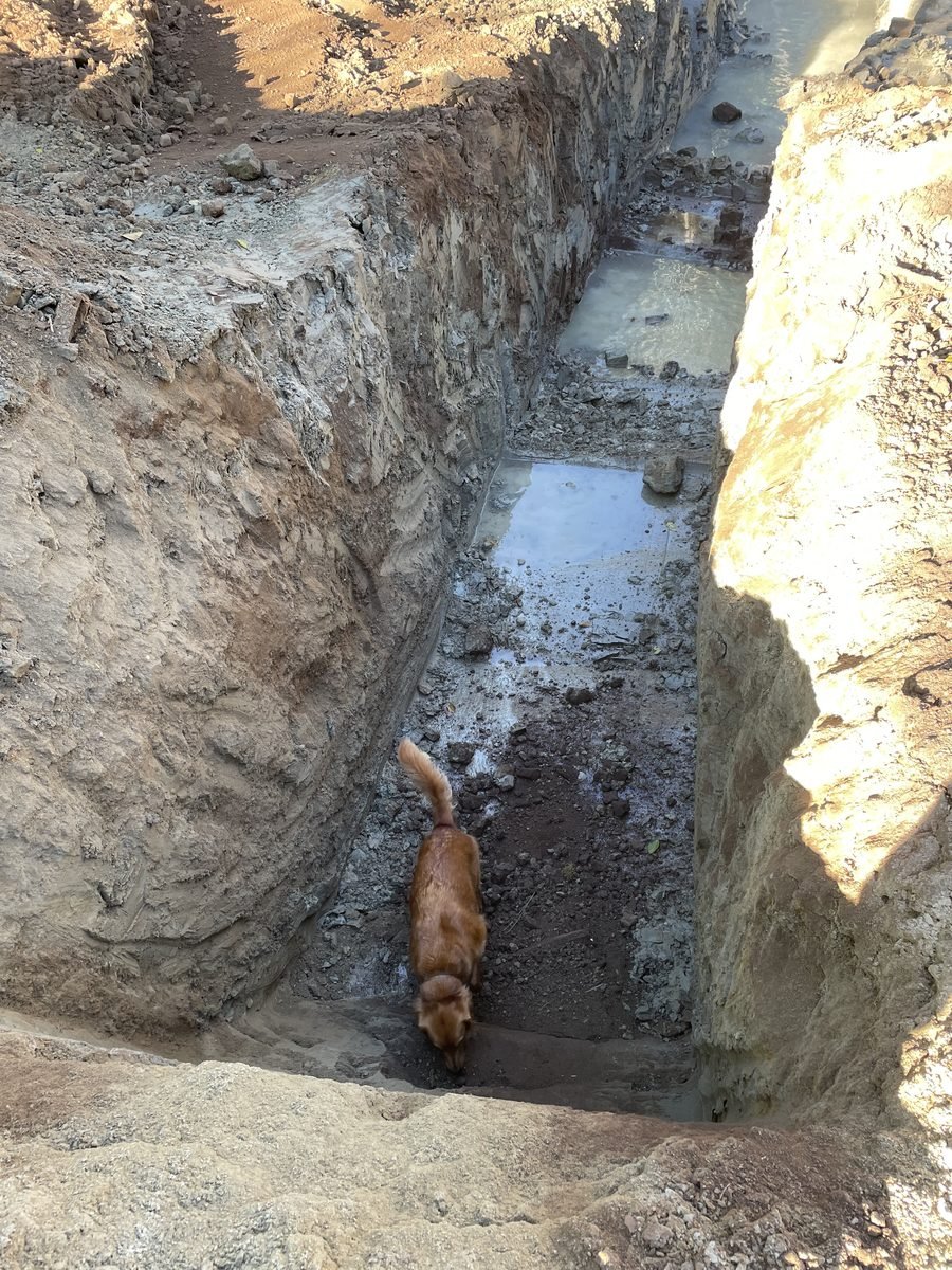Keyway trench at the base of the pond showing crushed rock fill and concrete well ring walls