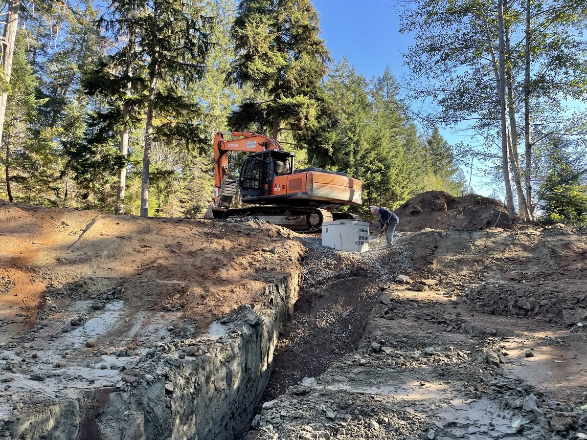 Concrete well ring being placed on crushed rock base at the bottom of the pond excavation